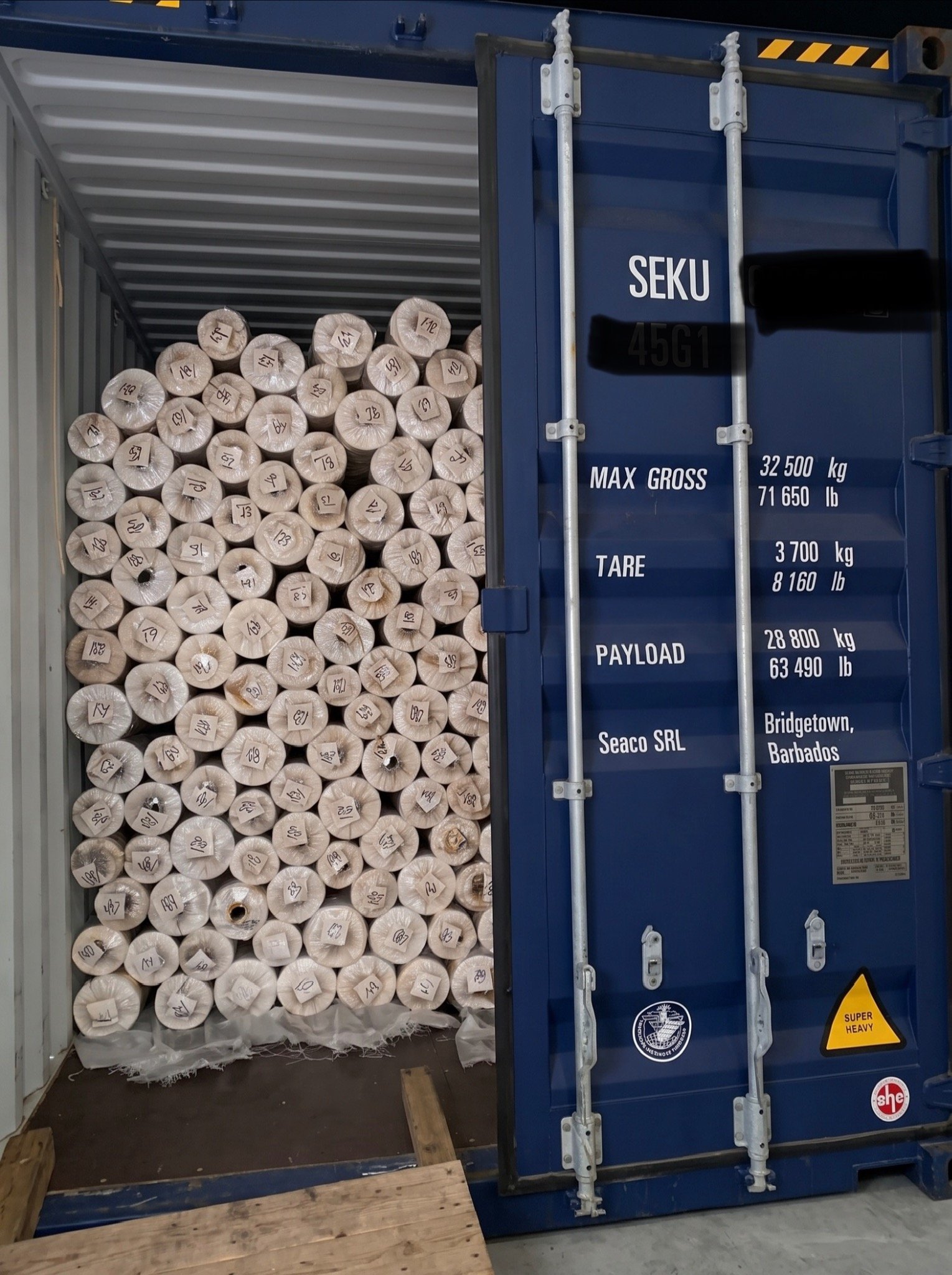 Packed fabric rolls visible inside a partially open shipping container